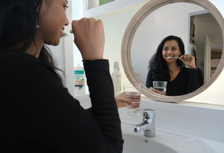 Image of a woman cleaning her teeth in the bathroom
